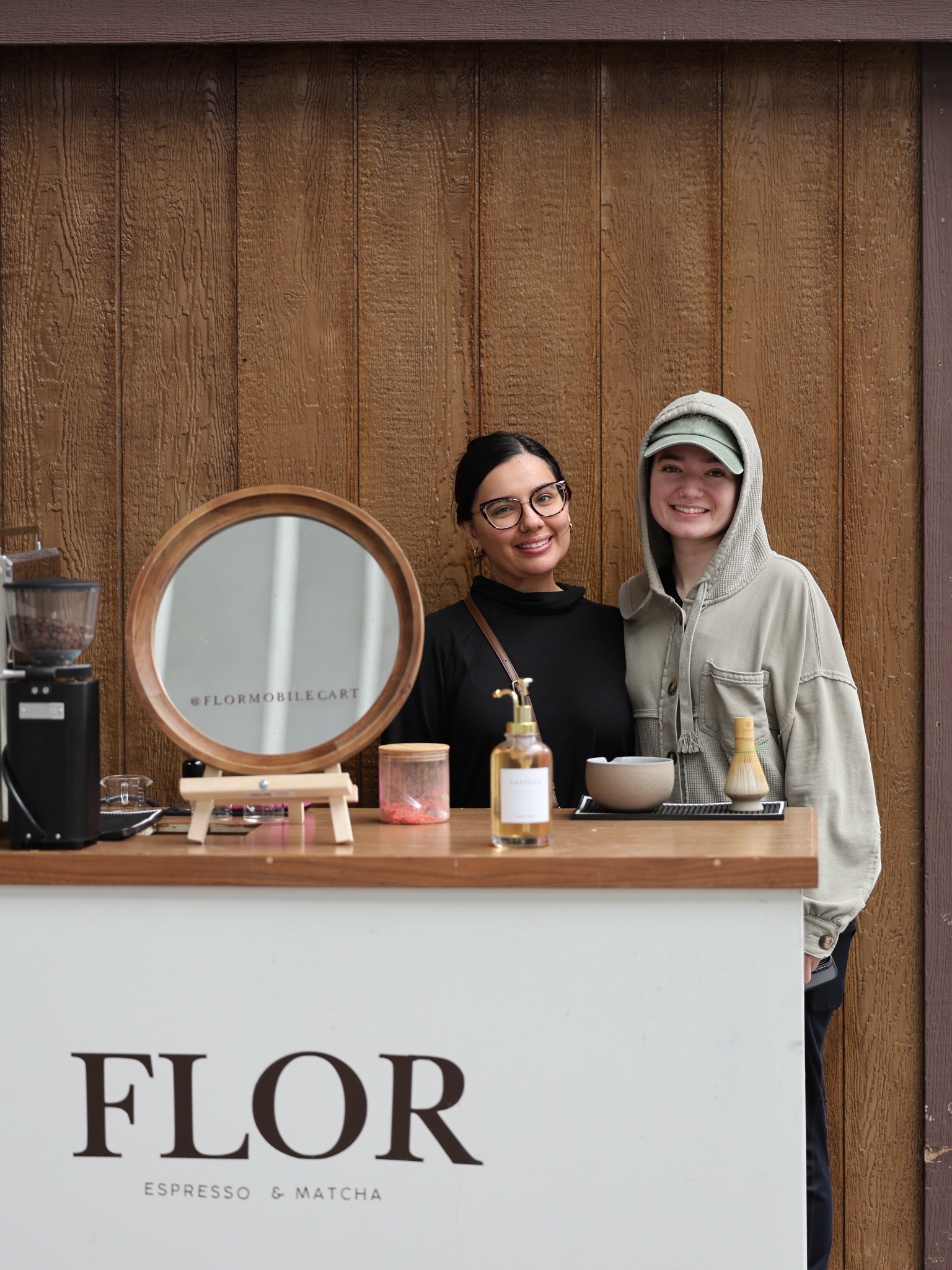 Two people smiling behind the FLOR coffee stand