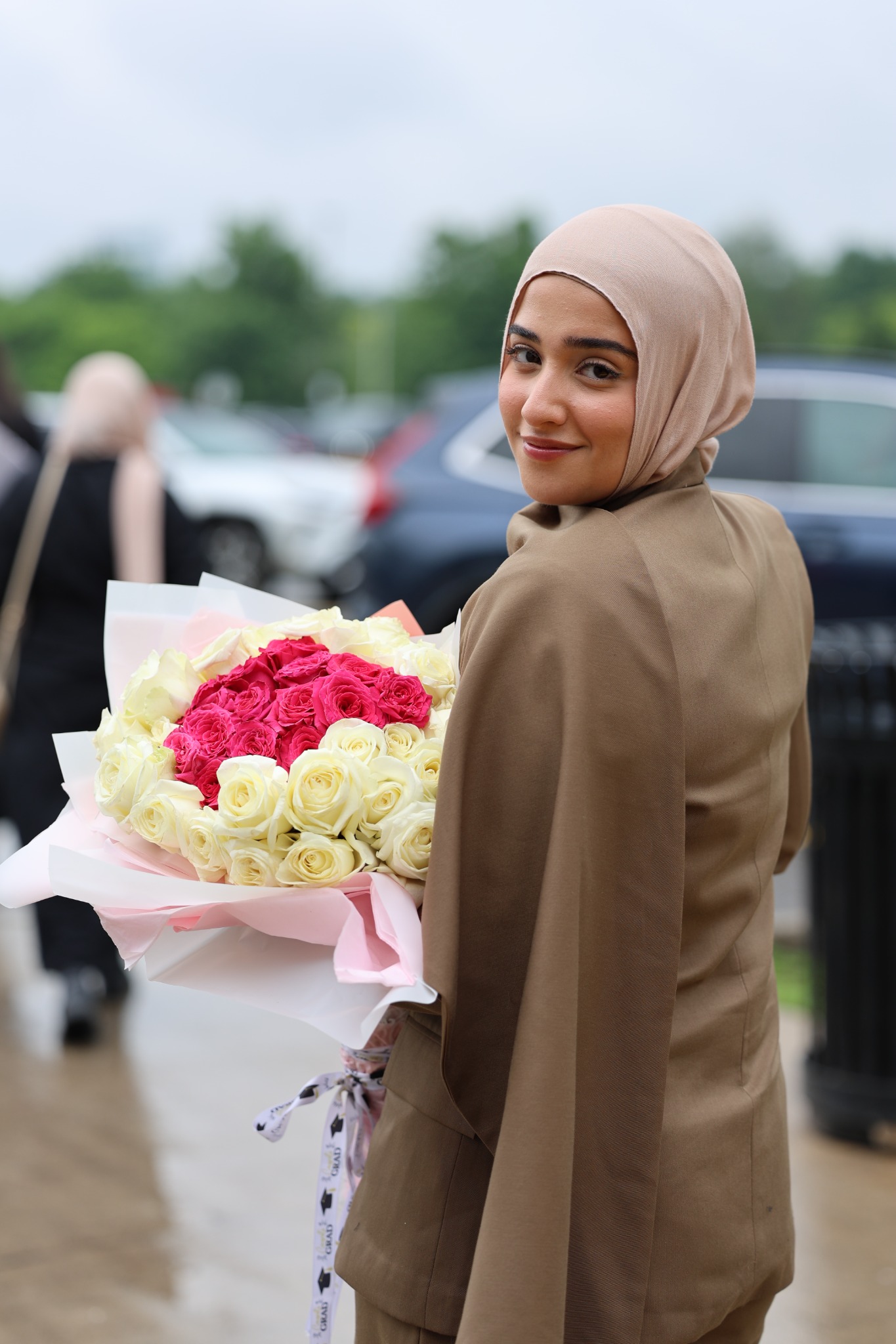 Graduate looking back while holding a bouquet outdoors