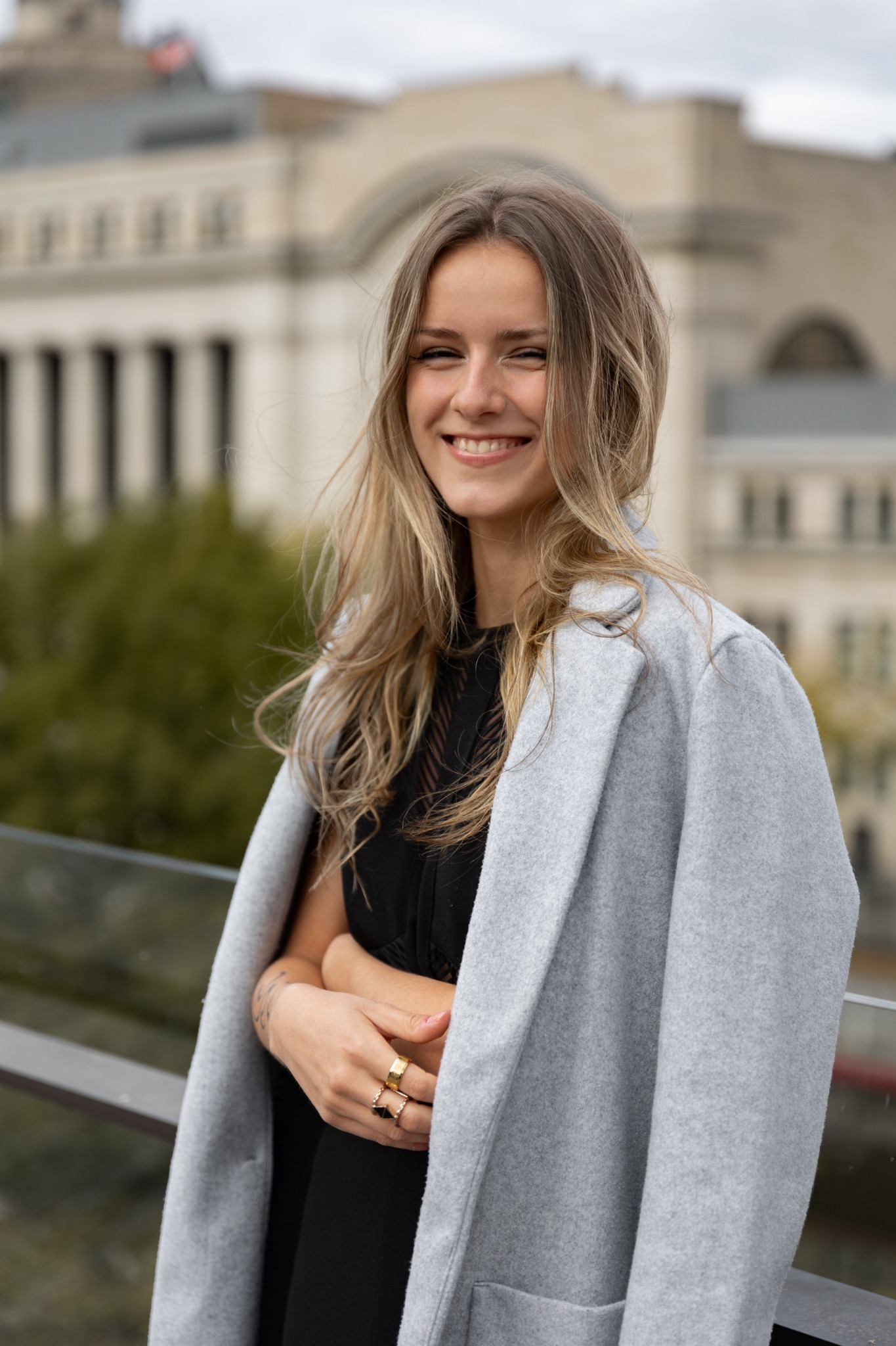 Smiling portrait with a light blue coat and historic architecture