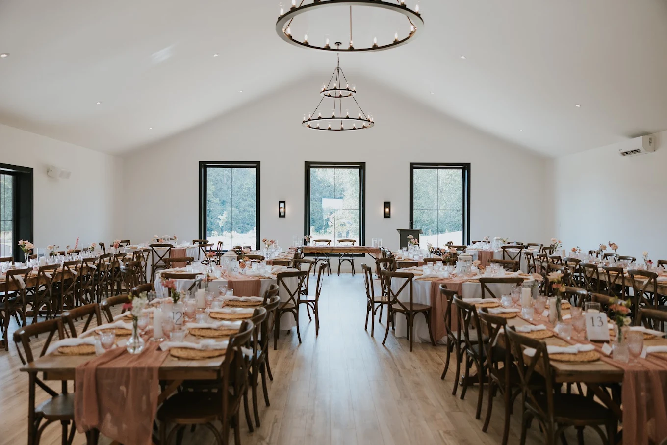 Wedding reception tables beneath circular chandeliers at Bleeks and Bergamot